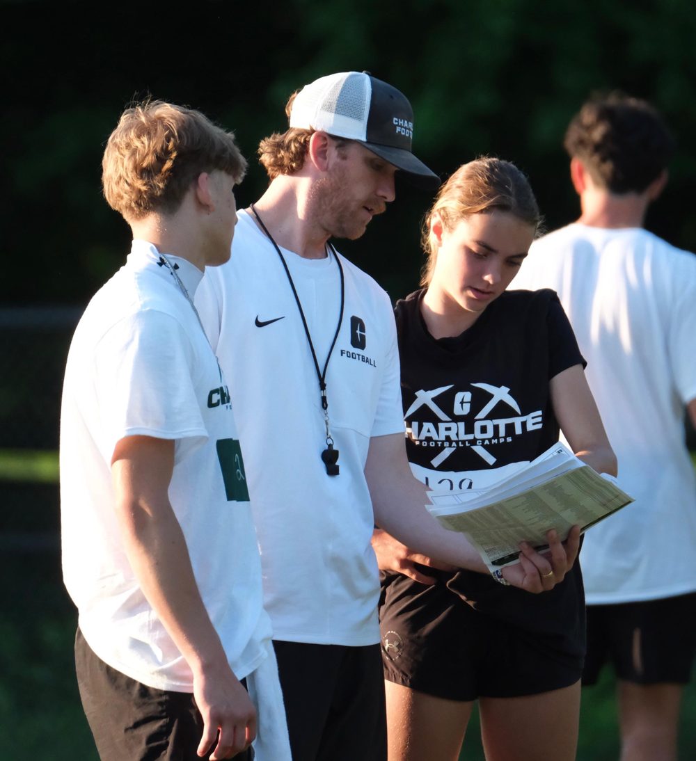 Kennedy Ford reading plays with a Charlotte football coach at camp